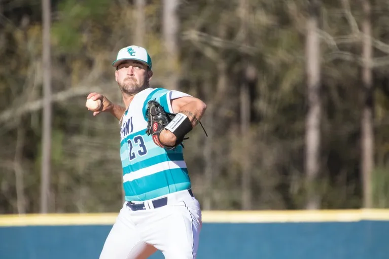 Un jugador de béisbol con uniforme azul y blanco está en el campo de juego en el campus del New Brunswick Community College.