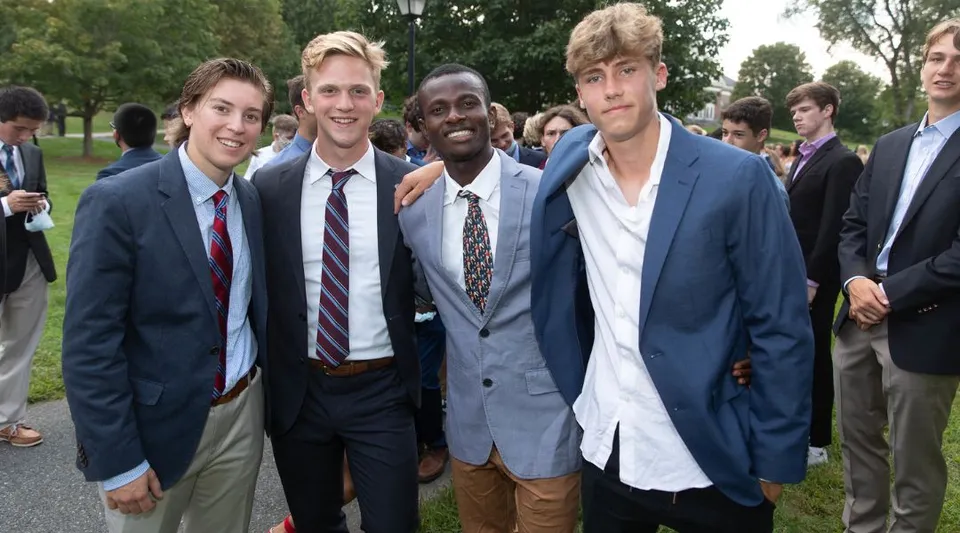 Un gruppo di studenti della Northfield Mount Hermon School è all'aperto davanti ad alberi verdi.