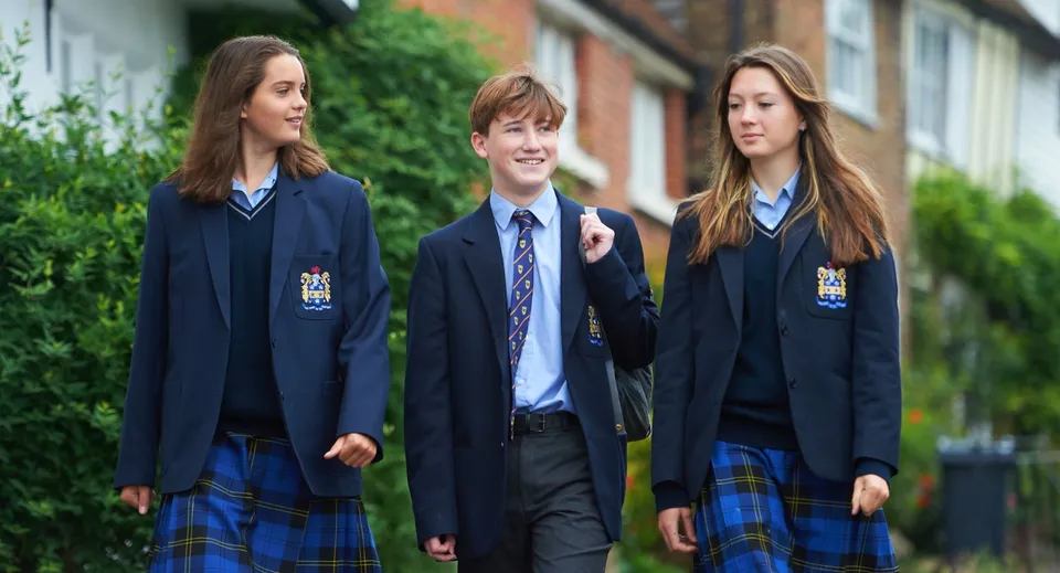 Tre studenti della Sutton Valence School camminano insieme su un viale accanto a un edificio in mattoni.