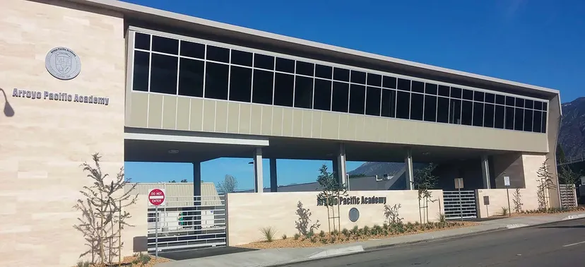 L'edificio principale moderno e su più piani della Arroyo Pacific Academy con grandi finestre contro un cielo azzurro terso.