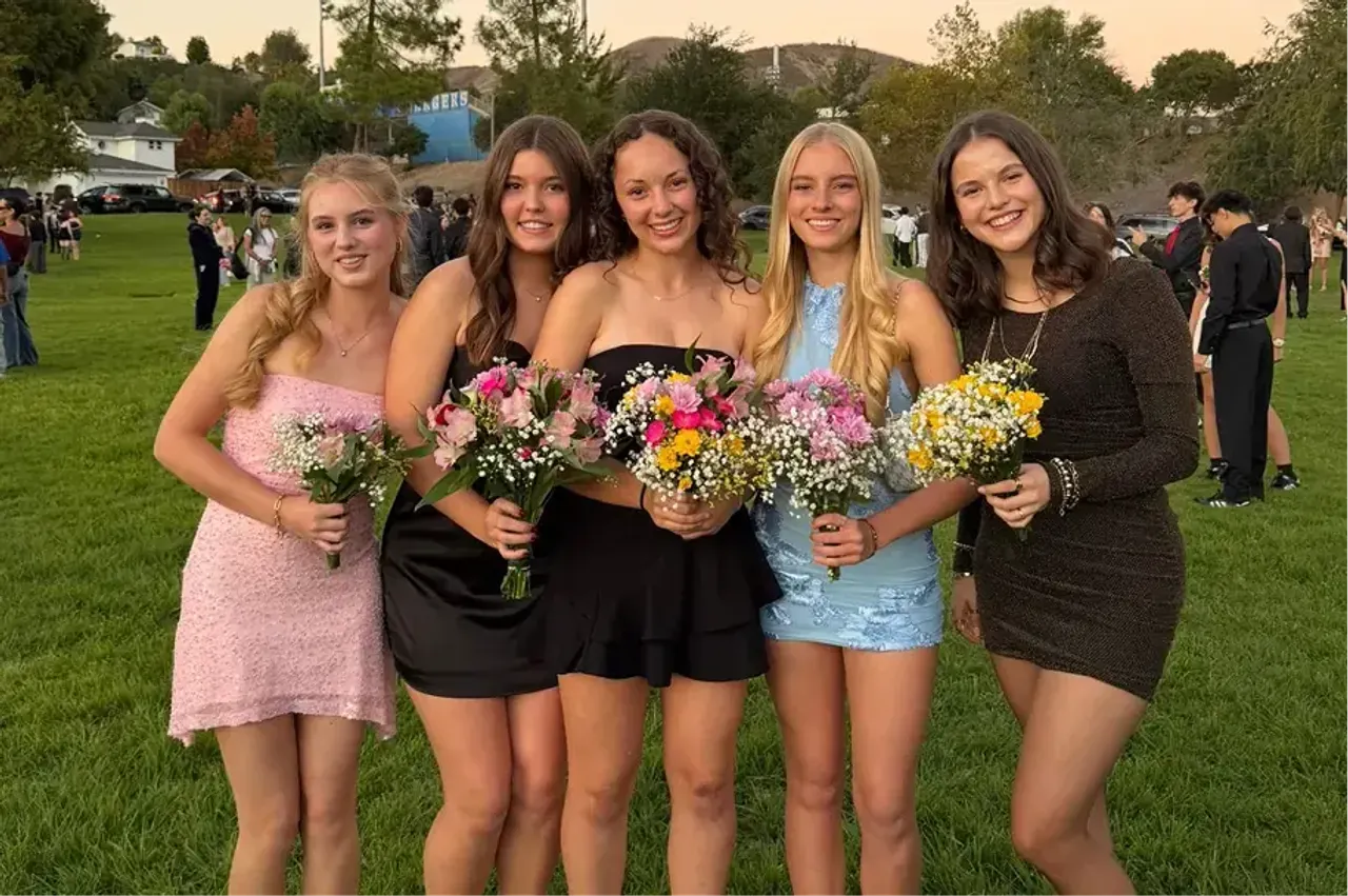 Cinque ragazze in abito elegante con mazzi di fiori a una festa scolastica al tramonto