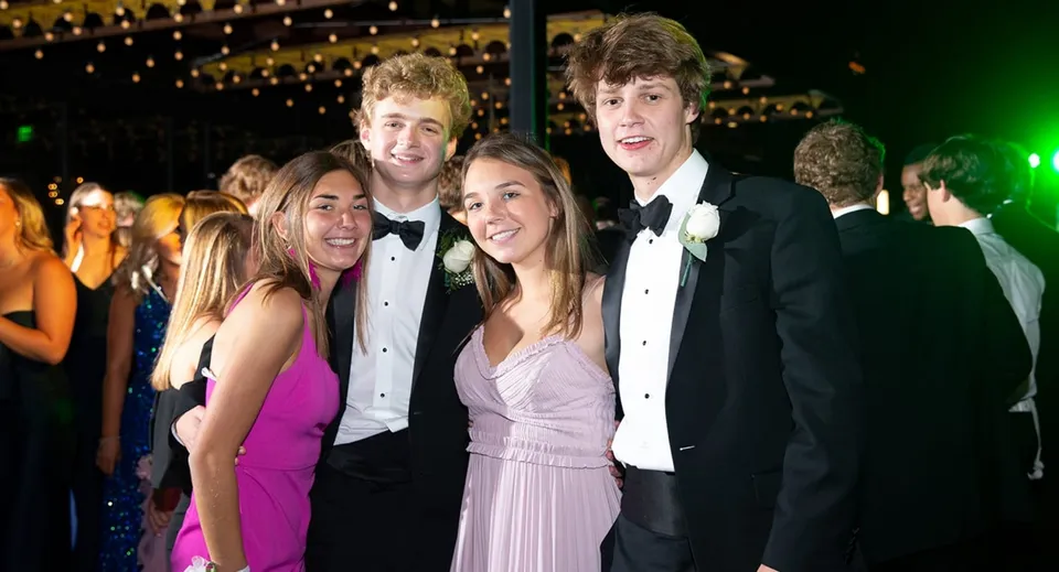 Un gruppo di studenti del St. David’s College posa insieme in abiti eleganti davanti a uno sfondo di luci scintillanti.