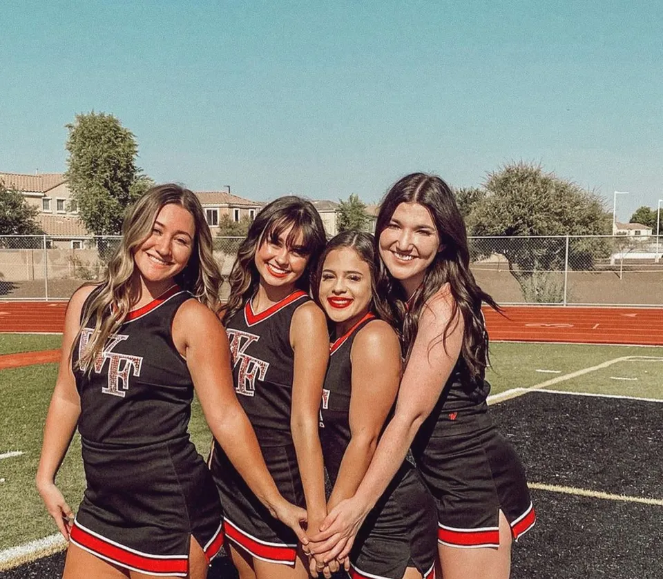 Quattro studentesse della Williams Field High School posano insieme sul campo sportivo davanti a edifici e alberi.