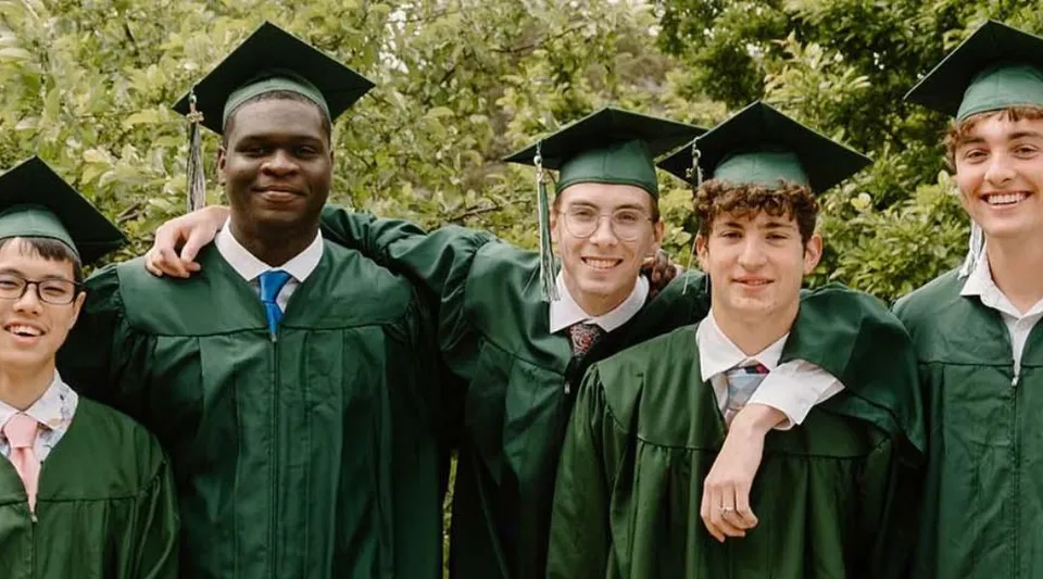 Un gruppo di diplomati in toga verde all'aperto nel campus della University Lake School.