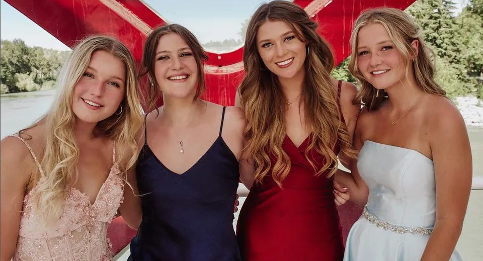 Quattro studentesse della Bishop Carroll High School sono insieme all'aperto davanti a uno sfondo rosso.