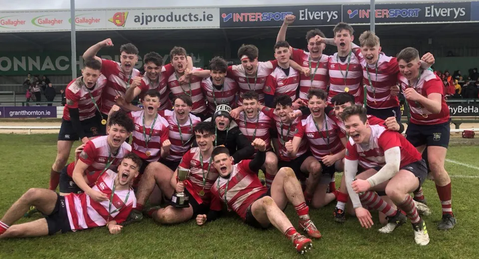 Un gruppo di giocatori di rugby del St. Muredach's College festeggia insieme sul campo sportivo.