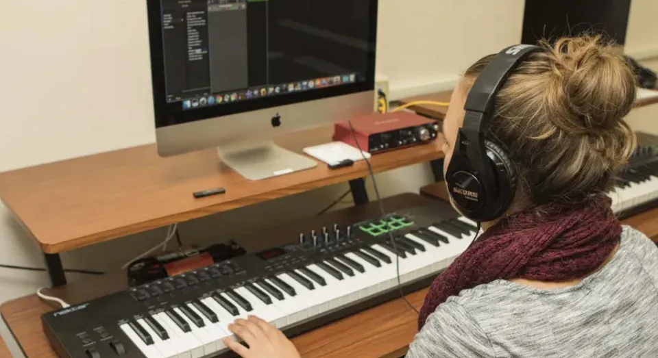Una persona con le cuffie è seduta a una scrivania nello studio musicale del Maine Central Institute.