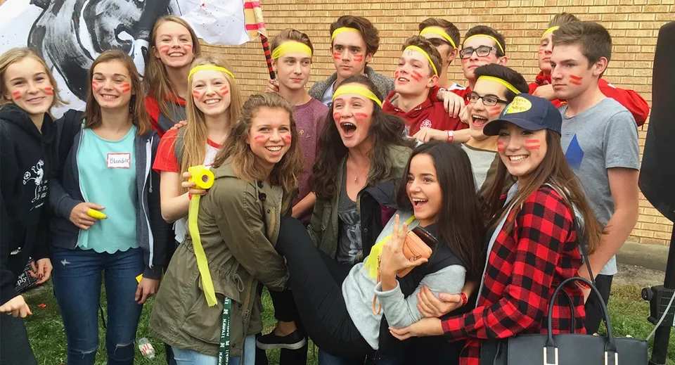 Un gruppo di giovani studenti e studentesse della Strathcona High School posa davanti a una parete in mattoni con graffiti.