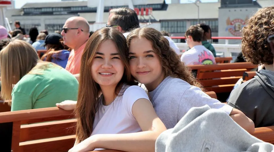 Due studentesse della Auburn Adventist Academy siedono insieme su una panchina all'aperto.