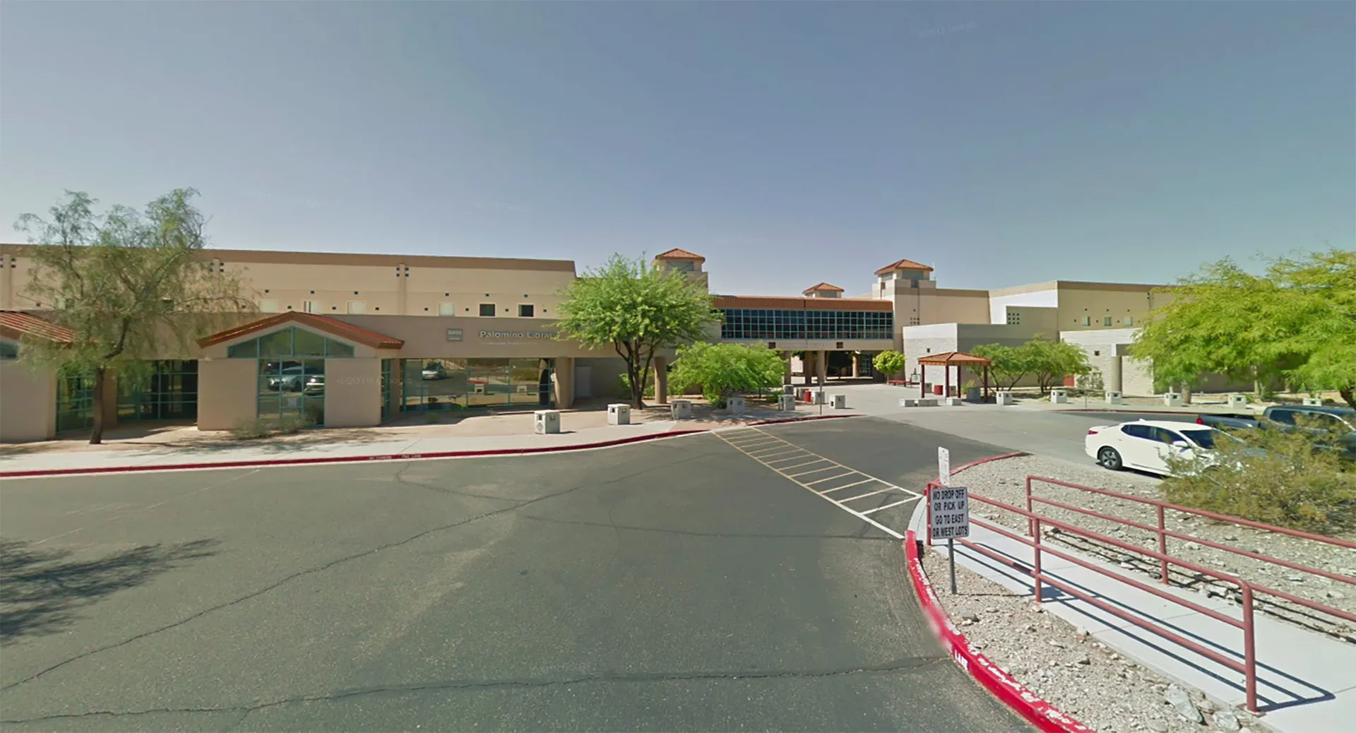 Un edificio scolastico dello Scottsdale Unified School District con parcheggio e alberi in primo piano sotto un cielo azzurro e limpido.