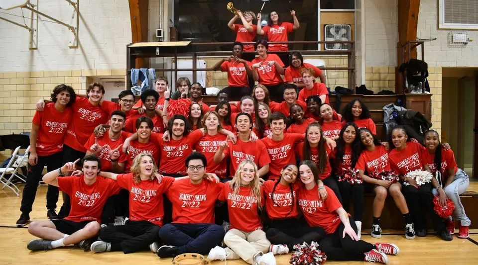 Un gruppo di studenti e studentesse della Wayland Academy in maglietta rossa si riunisce in una palestra.