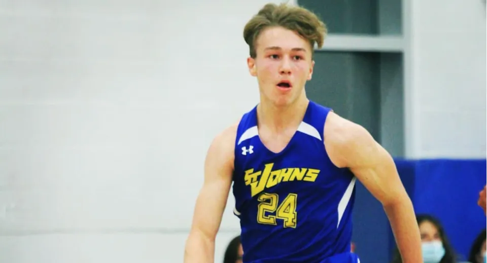 Uno studente della St. Johns High School sta sorpreso sul campo da basket con una maglia blu e il numero 24.