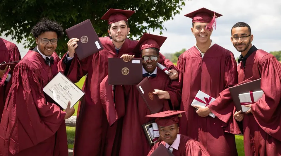 Diplomate e diplomati della Church Farm School si trovano insieme all'aperto tenendo in mano i loro diplomi.