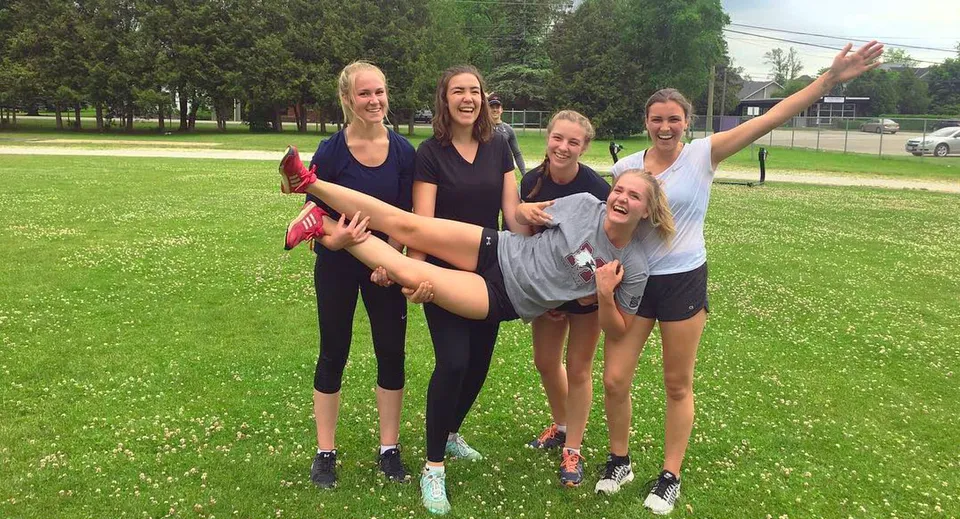 Un gruppo di giovani studentesse sta ridendo su un prato nel parco del campus del Collingwood Collegiate Institute.