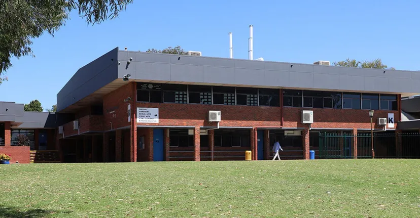 L'edificio moderno in mattoni a più piani della Morley Senior High School si erge dietro un campo verde.