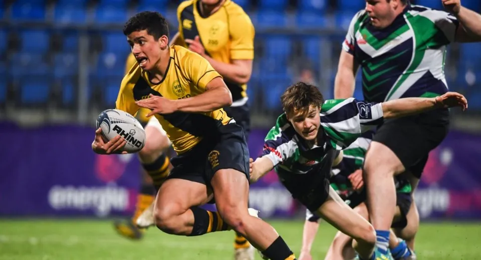 Studenti di The Kings Hospital giocano a rugby e lottano durante un placcaggio sul campo da gioco.