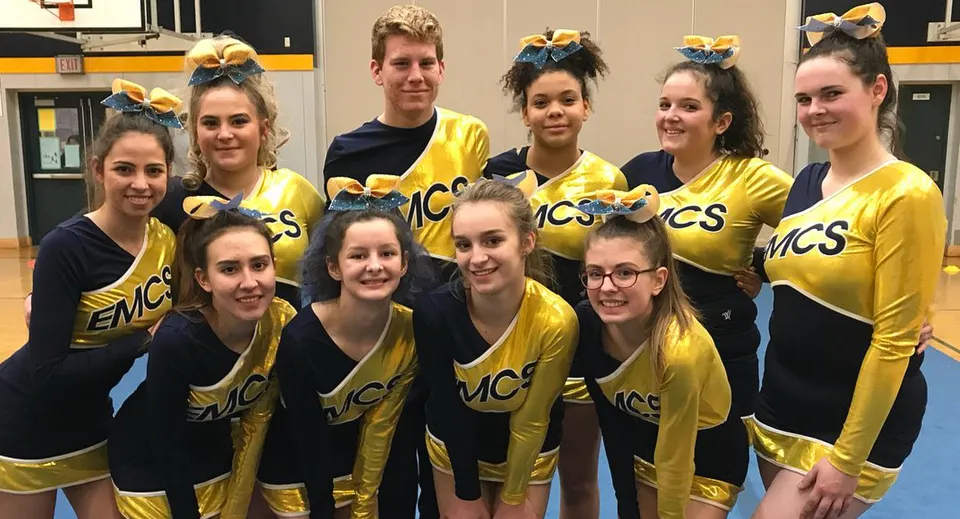 La squadra di cheerleading della Edward Milne Community School posa insieme nella palestra.