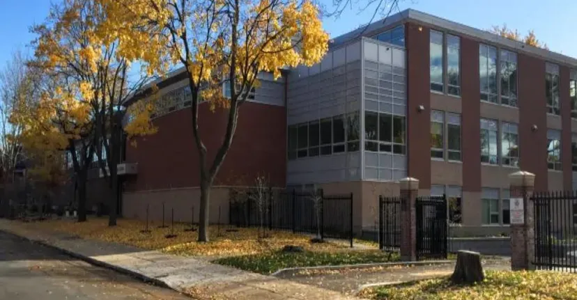 L'edificio moderno del Lower Canada College è circondato da alberi con foglie autunnali gialle e mostra un percorso pavimentato in primo piano.