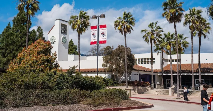 L'edificio principale bianco con torre dell'orologio nel campus del Santa Barbara City College è circondato da palme e un sentiero.
