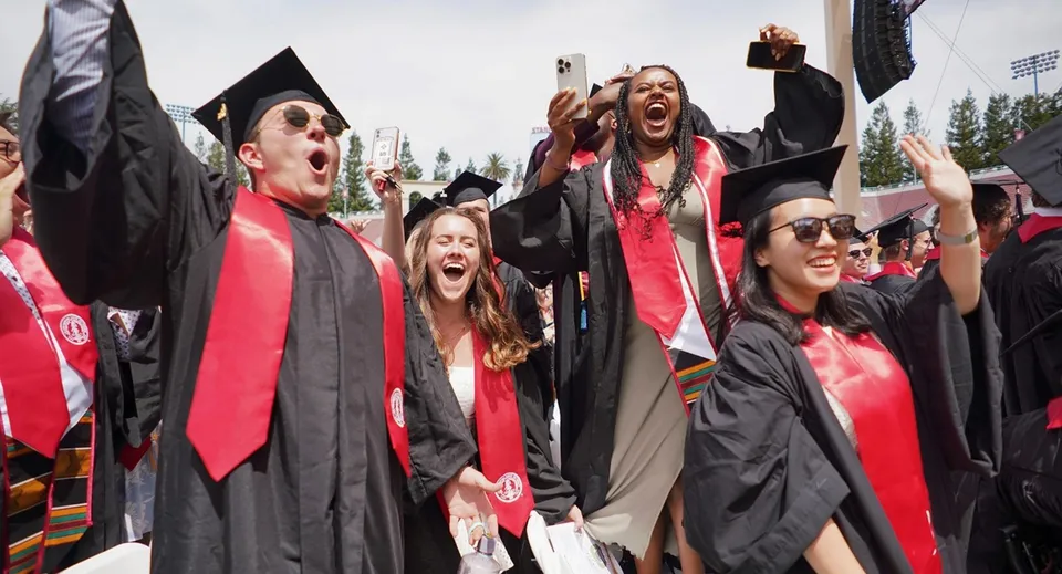 Un gruppo di diplomandi festeggia il diploma in toga nera e rossa sul campus della Westview Freedom Academy.