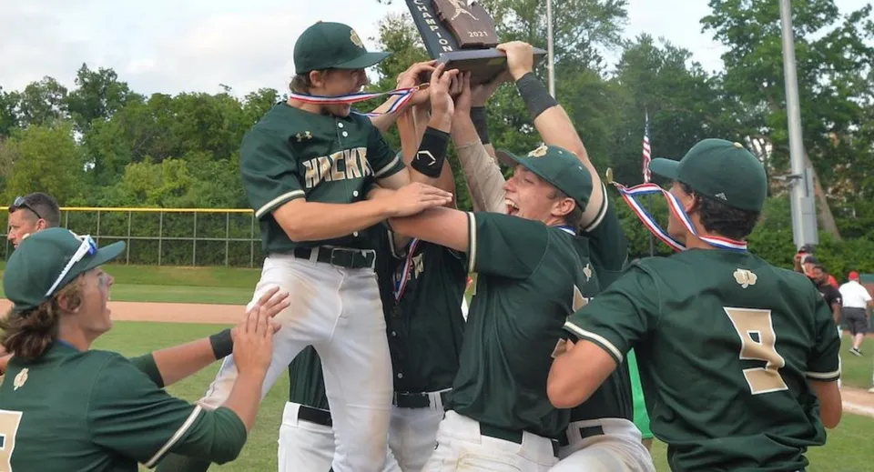 Un gruppo di studenti della Hackett High School in divisa verde festeggia insieme sul campo da baseball.