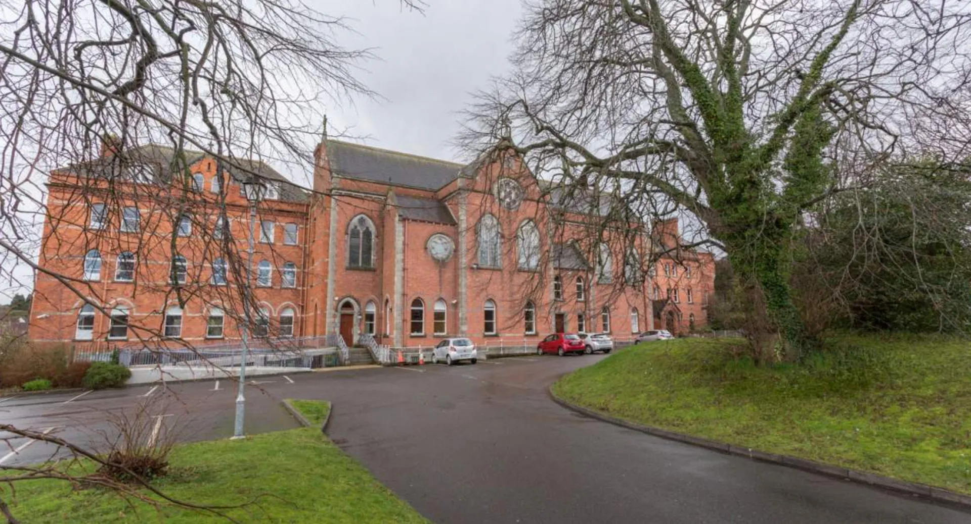 Il grande edificio in muratura con la torre dell'orologio nel terreno del Dominican College a Wicklow è circondato da alberi spogli.