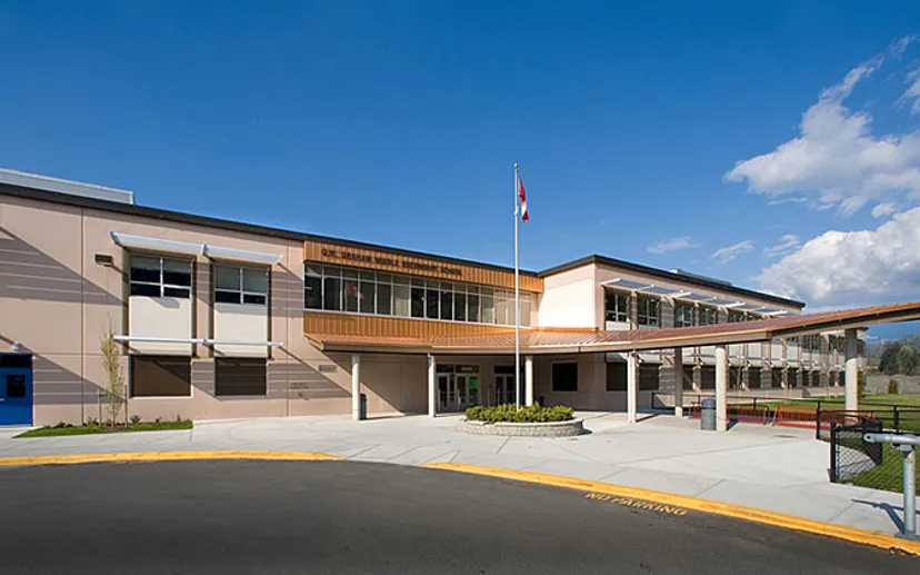 L'edificio a più piani della G.W. Graham Secondary School con un pennone e curati spazi esterni sotto un cielo blu.