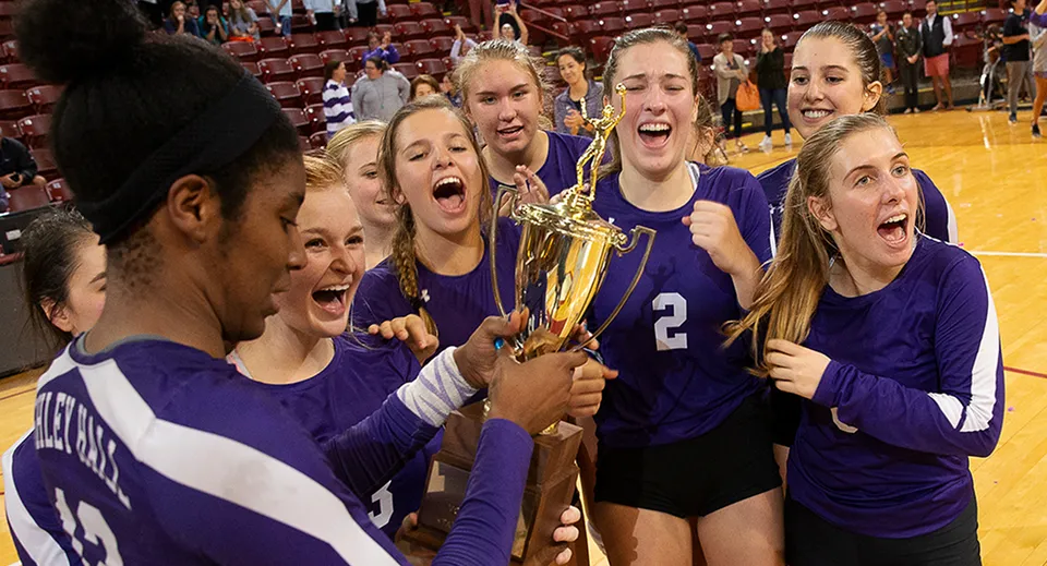 Studentesse della Ashley Hall School festeggiano con una coppa nella palestra dopo una vittoria a pallavolo.