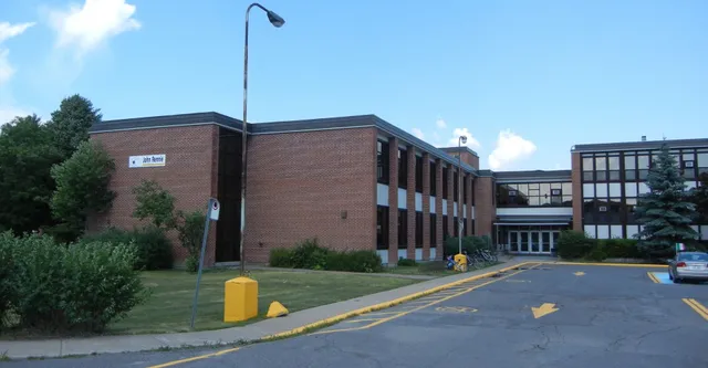 L'edificio in mattoni della John Rennie High School è circondato da aree verdi e si vede sotto un cielo azzurro e limpido.