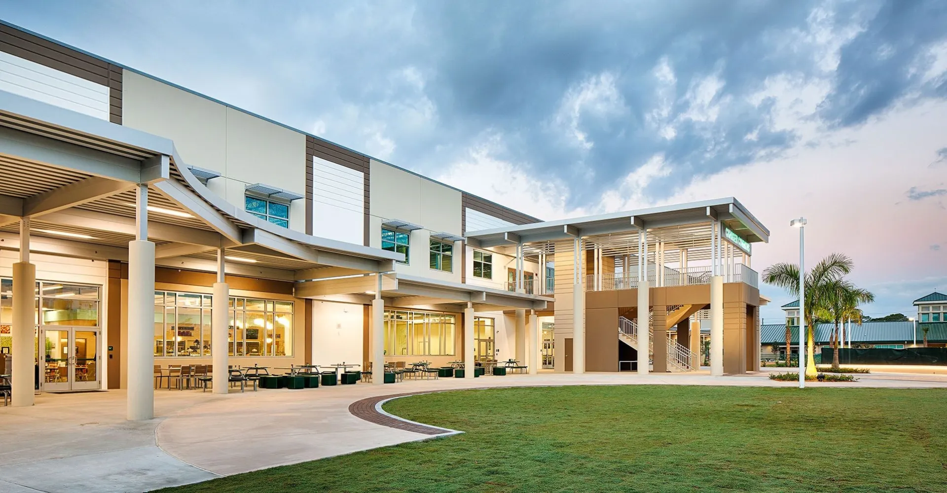 L'edificio moderno a più piani della Shorecrest Preparatory School con facciata in vetro e un cortile interno verde con cielo nuvoloso.