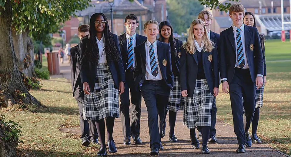Un gruppo di studenti della Oakham School cammina insieme su un sentiero circondato da alberi e verde.