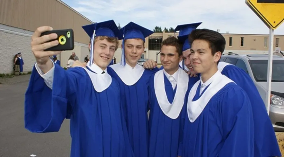 Un gruppo di giovani in toga da diploma blu scatta un selfie nell'area della Mount Elizabeth Middle/Secondary School.