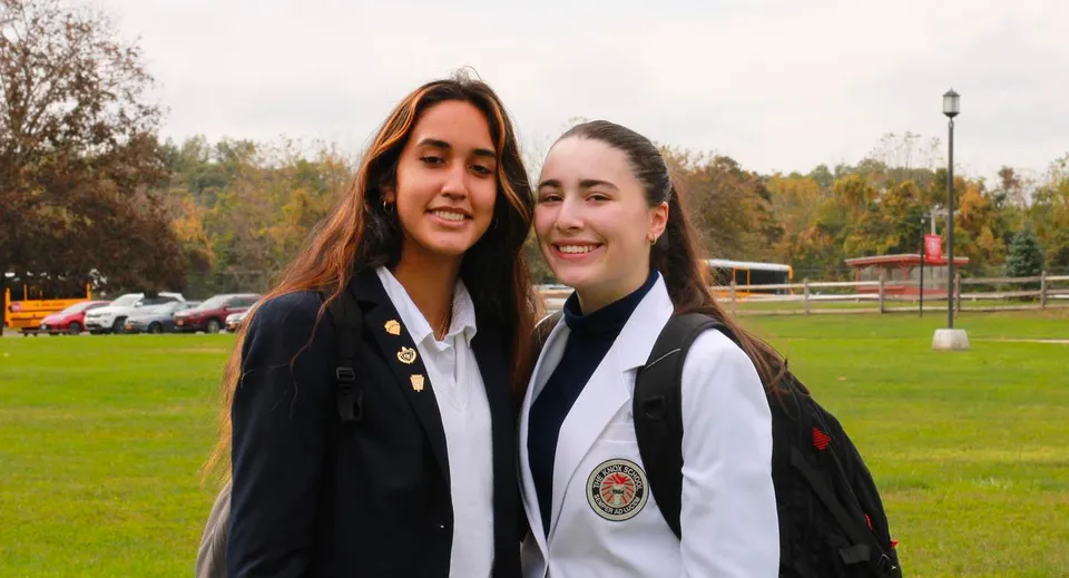 Due studentesse della The Knox School sorridono su un prato davanti a un edificio.