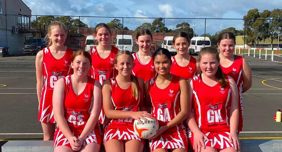 Un gruppo di giovani giocatrici di netball in maglia rossa si trova sul campo all'aperto della Bordertown High School.