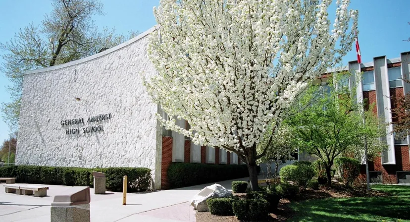 L'grande edificio bianco con facciata curva nel campus della North Star High School è circondato da alberi in fiore.