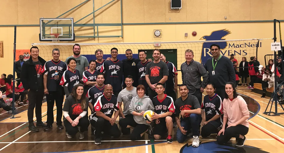 Un gruppo di studenti della A.R. MacNeill Secondary School posa nella palestra con canestri da basket sullo sfondo.
