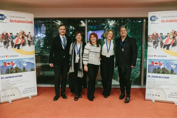 Cinco personas posan sonriendo entre dos pancartas publicitarias en un evento interior