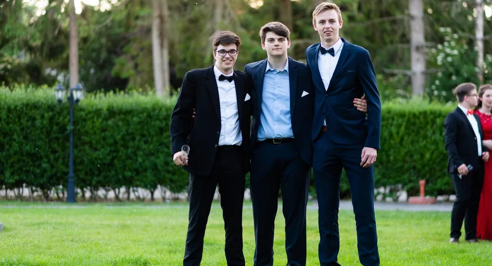 Tre ragazzi in divisa formale sono insieme su un prato nel campus della Monmouth School for Boys.
