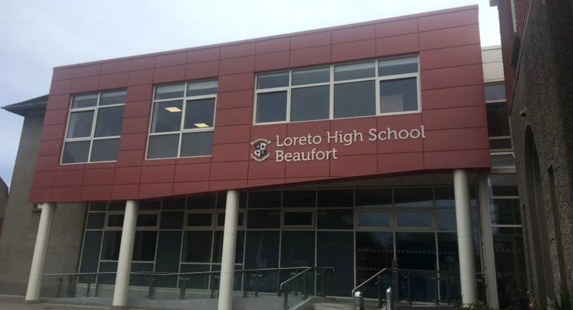 L'edificio scolastico moderno rosso e grigio della Loreto High School Beaufort mostra chiaramente il nome della scuola sulla facciata.