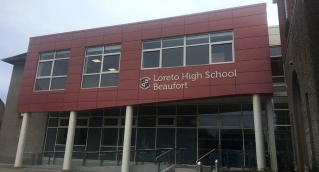 L'edificio scolastico moderno rosso e grigio della Loreto High School Beaufort mostra chiaramente il nome della scuola sulla facciata.