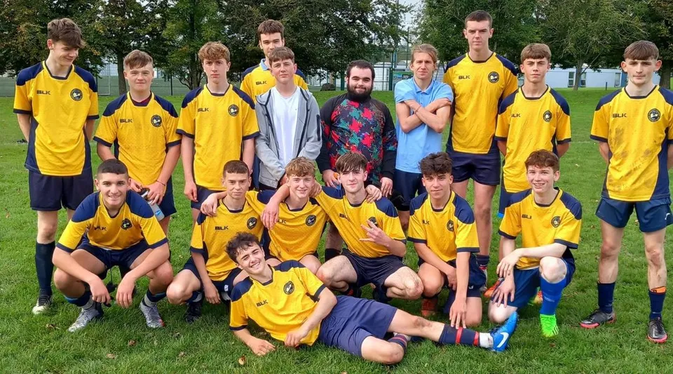 Un gruppo di giovani calciatori posa su un campo da gioco nel campus del Carrignafoy Community College.