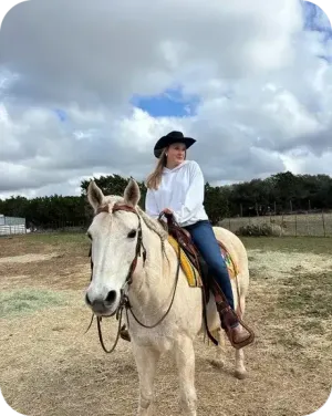 Ida cavalca un cavallo bianco con cappello da cowboy in un ranch negli Stati Uniti