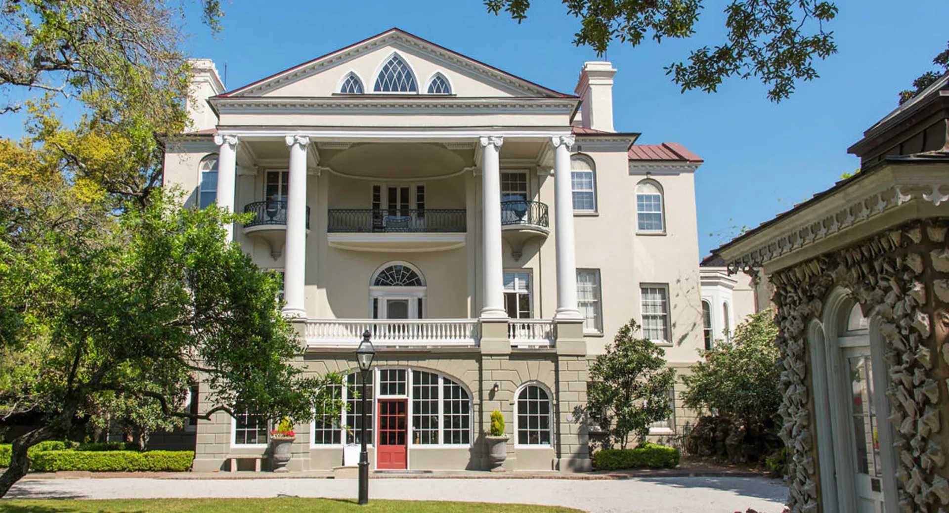 L'edificio storico con colonne e balconi nel campus della Ashley Hall School è circondato da alberi e una verde vegetazione.