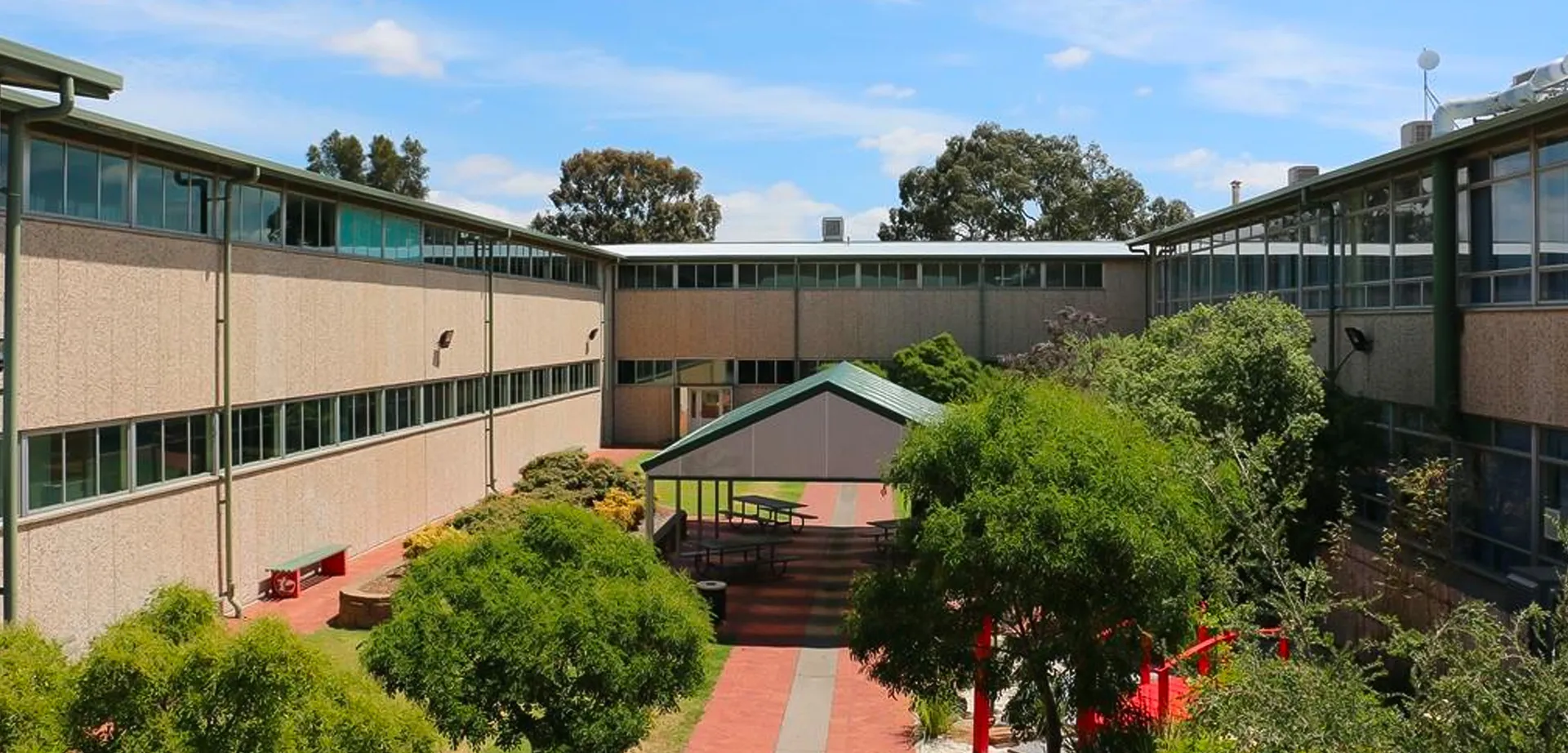 L'edificio a più piani con cortile interno della Modbury High School è circondato da alberi e cespugli.