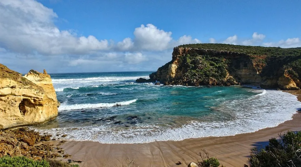 Un pittoresco paesaggio costiero con spiaggia di sabbia e scogliere davanti all'edificio della Hunters Hill High School.