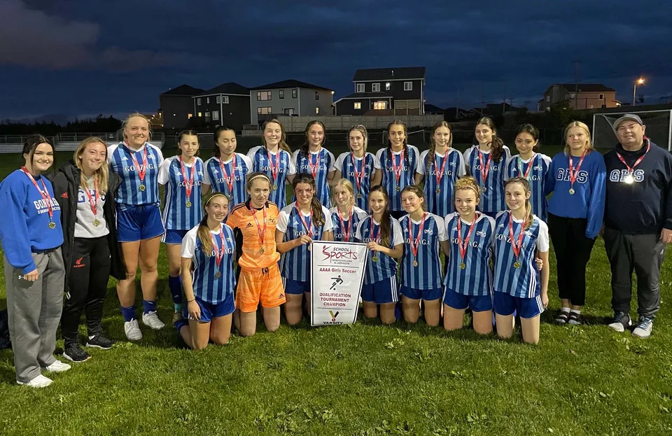 Un gruppo di calciatrici della Gonzaga High School si trova insieme di notte su un campo da gioco.