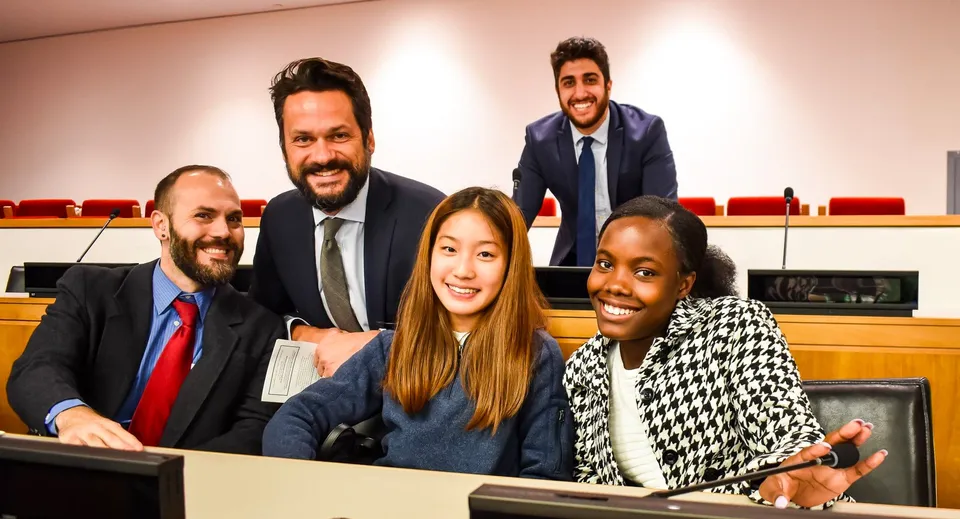 Un gruppo vario di studenti della Winchendon School a New York City è seduto insieme in una sala riunioni professionale.