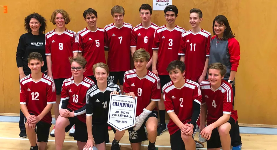 La squadra di pallavolo della Revelstoke Secondary School posa con il trofeo del campionato in palestra.