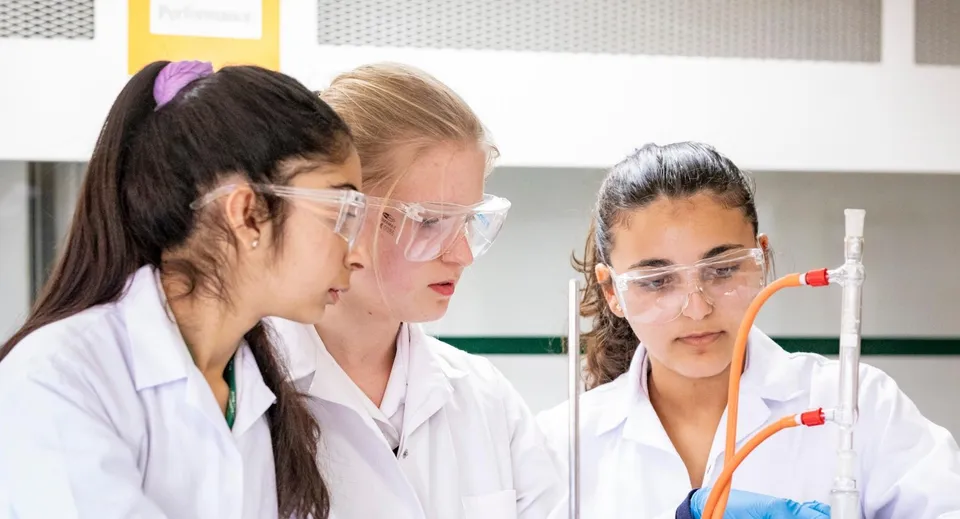 Tre studentesse della Marymount International School analizzano un campione in una provetta all'interno del laboratorio.