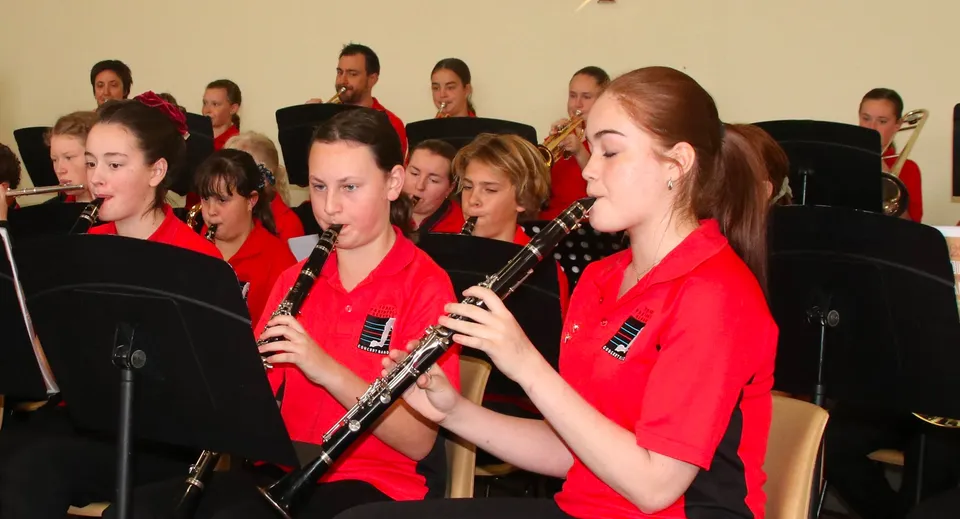 Studenti della Central Yorke School in divisa rossa che suonano come ensemble musicale su un palco.